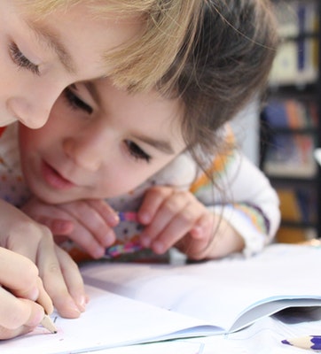 girls-on-desk-looking-at-notebook-159823