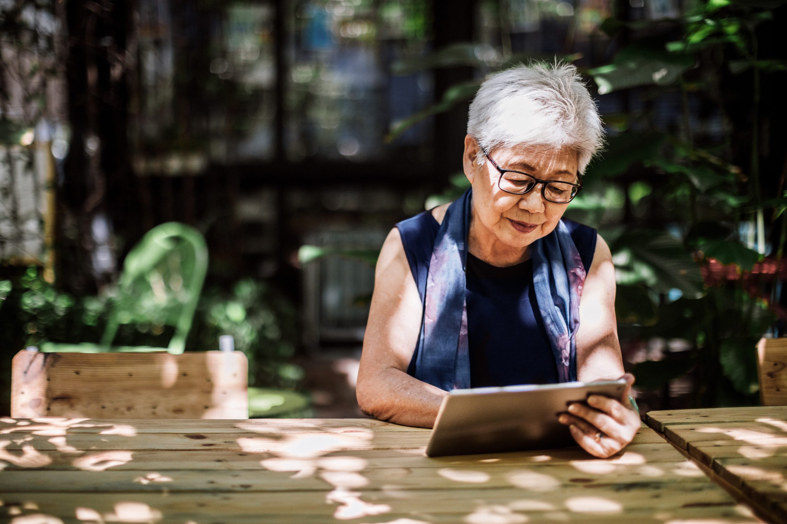 Senior Woman Using Digital Tablet Senior woman sitting alone and surfing the net on digital tablet