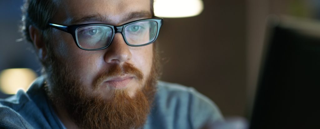 A man looking at a screen with strained eyes